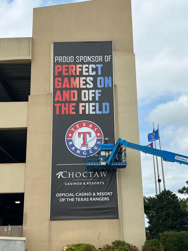 A man in a crane is putting up a sign on the side of a building.