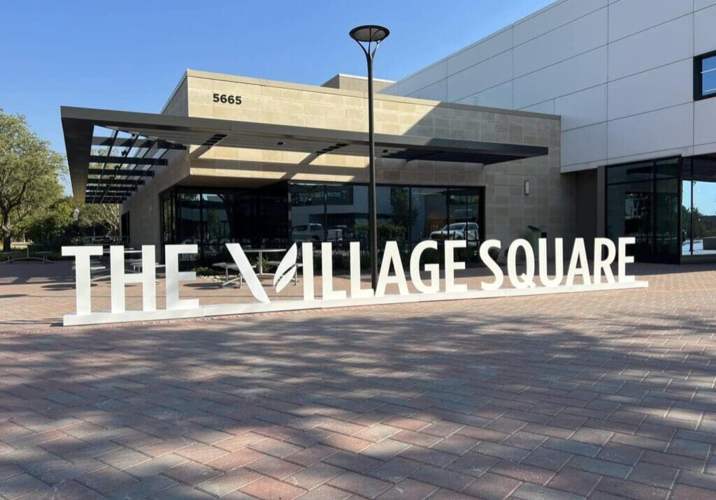 A large sign that says the village square.